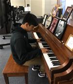 Boy playing piano in music class 